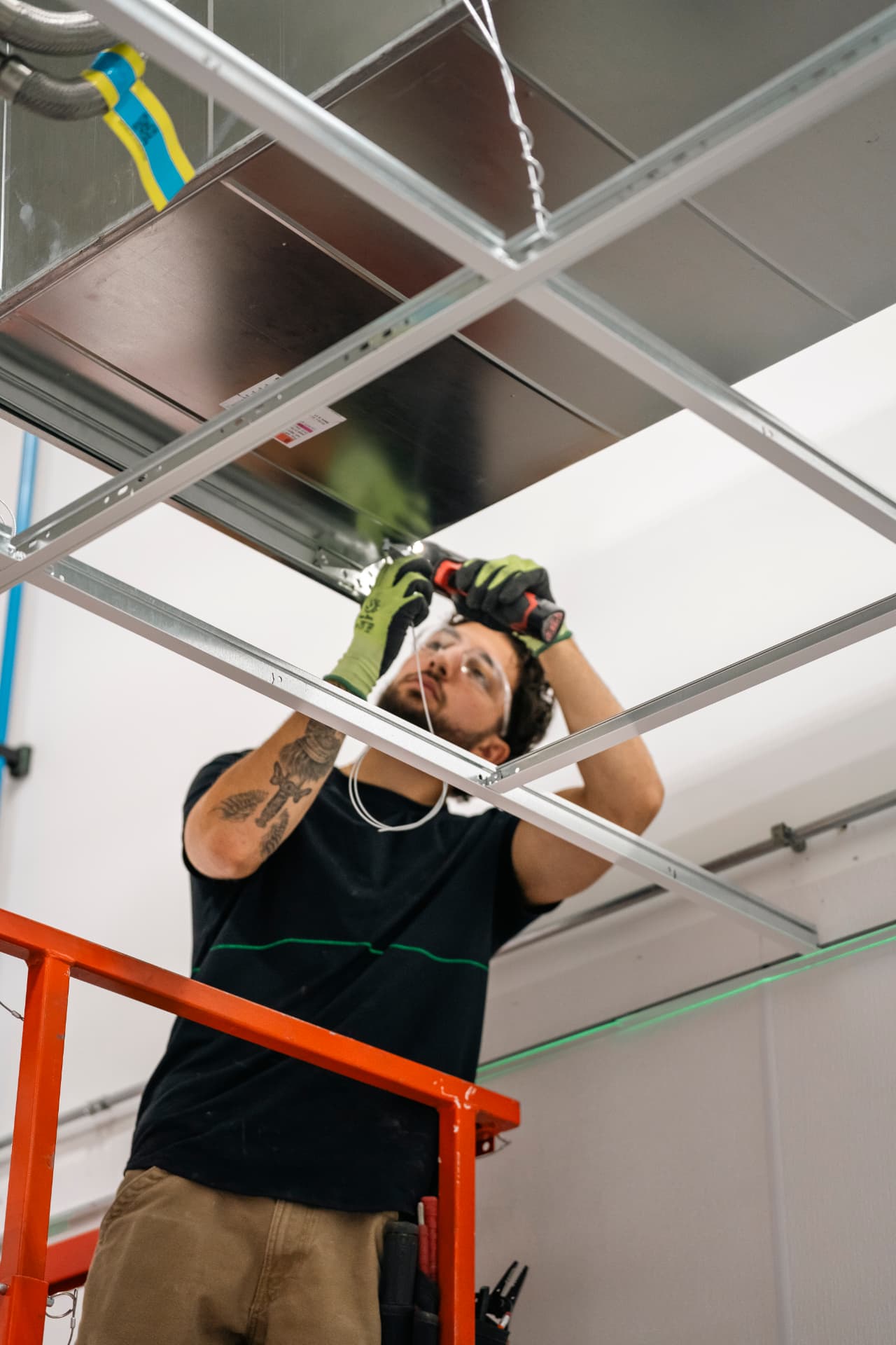 Installer setting suspended ceiling grid during a commercial tenant build-out