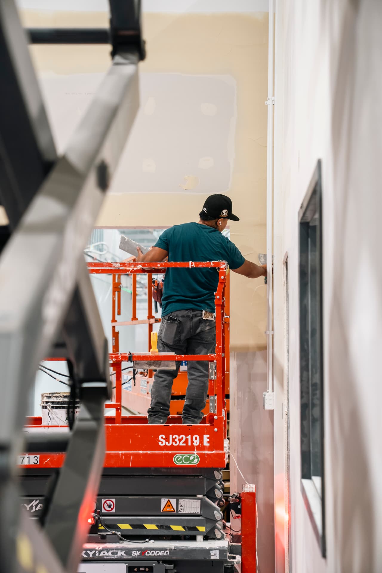 Drywall repair work from a scissor lift inside an occupied commercial building