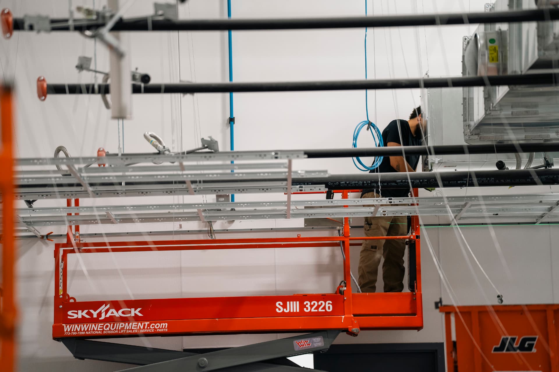 Bauer-Build trade partner installing overhead systems from a scissor lift on a commercial job site